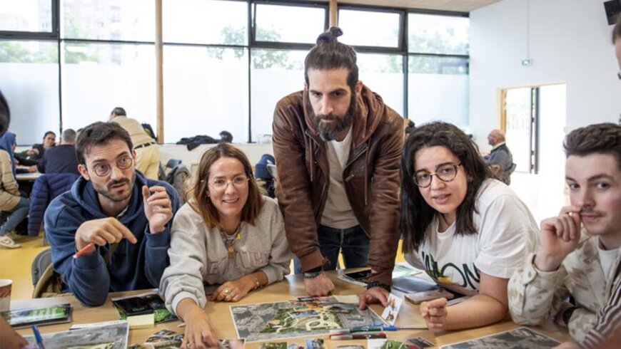 5 personnes sont réunis autour d'une table avec un plan du parc et de photos représentants divers plantes, mobilier, etc. Ils discutent, l'ambiance est joviale. 
