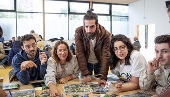 5 personnes sont réunis autour d'une table avec un plan du parc et de photos représentants divers plantes, mobilier, etc. Ils discutent, l'ambiance est joviale. 