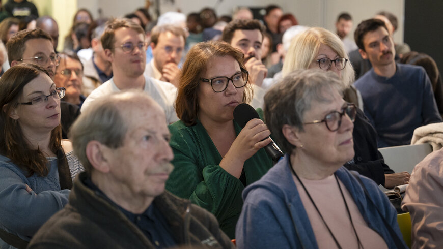 Au milieu de la foule, une habitante prend la parole pour poser une question. 