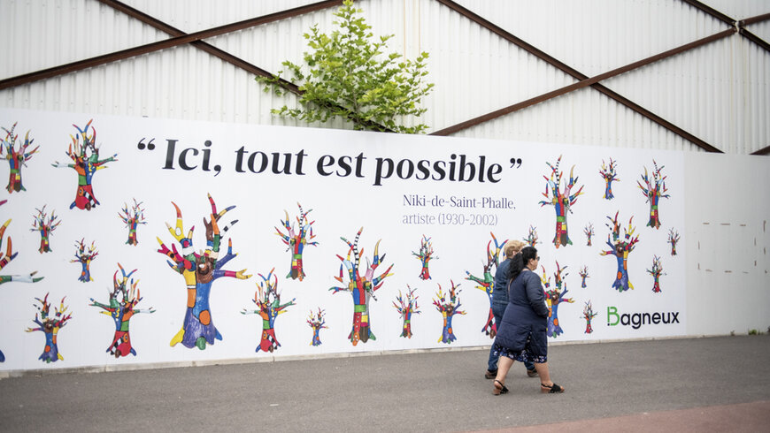 Une personne marche devant un grand panneau. Il est écrit : ici tout est possible