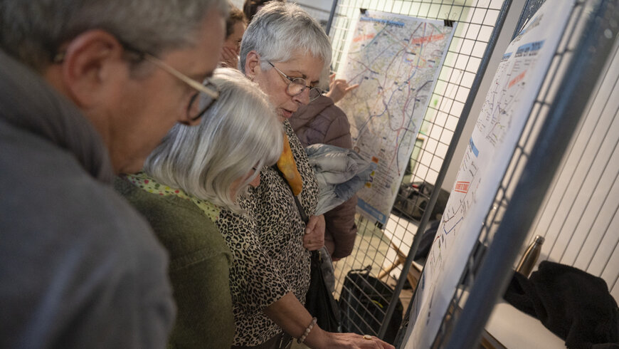une demi douzaine de personnes, debouts, lisent les panneaux explicatifs des travaux à venir.